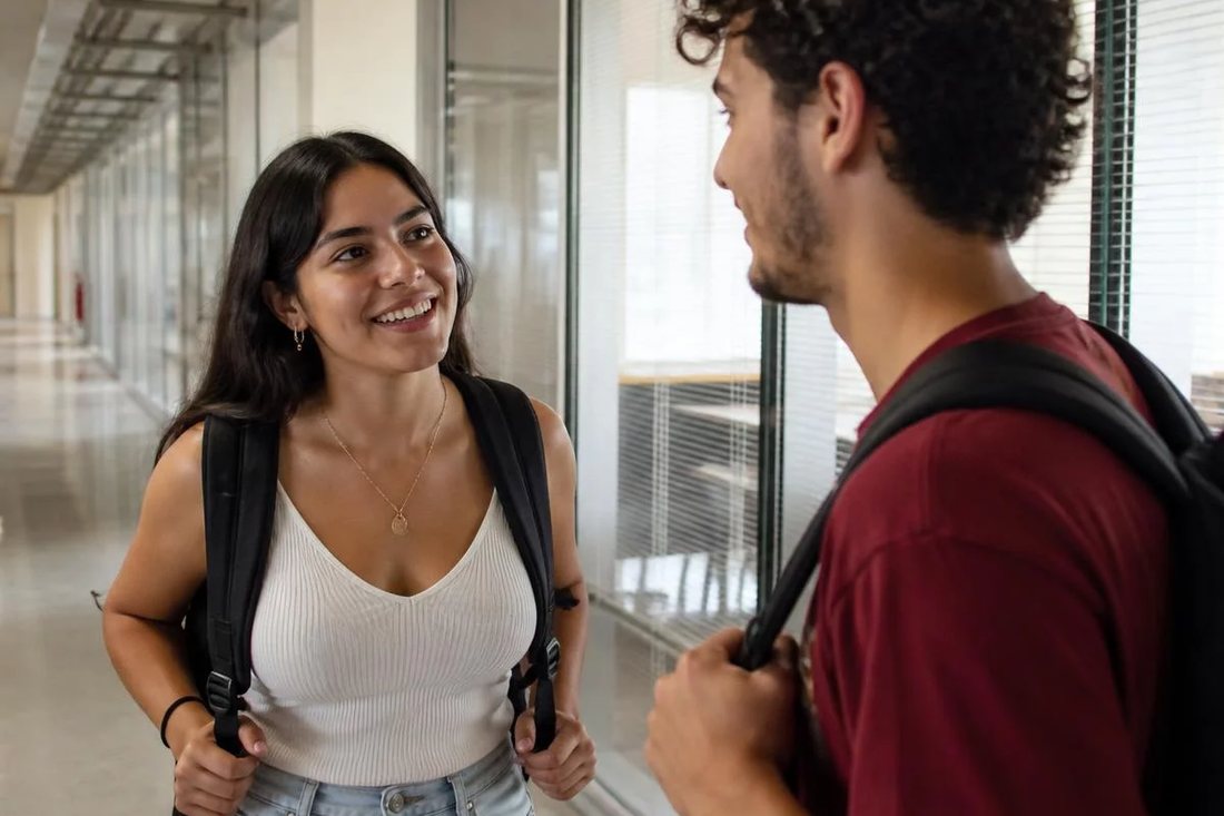 Dois estudantes de mochila continuam a discussão no corredor depois da sessão